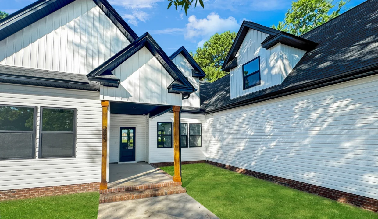 Exterior view of The Belhaven model home in Elizabeth City, NC, featuring white siding, black trim, and wood porch columns.