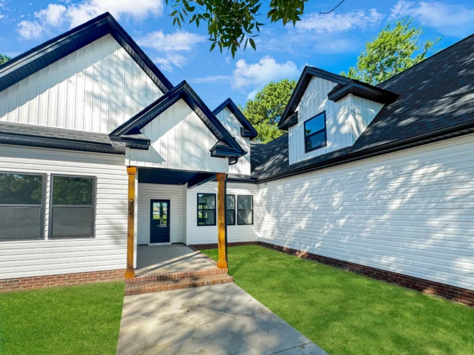 Exterior view of The Belhaven model home in Elizabeth City, NC, featuring white siding, black trim, and wood porch columns.